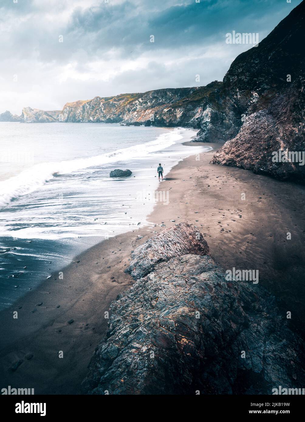 This image was captured at Caerthillian Cove in Cornwall, showing Paul wandering down the beach. UK: THESE STUNNING images of a lone traveller crossin Stock Photo
