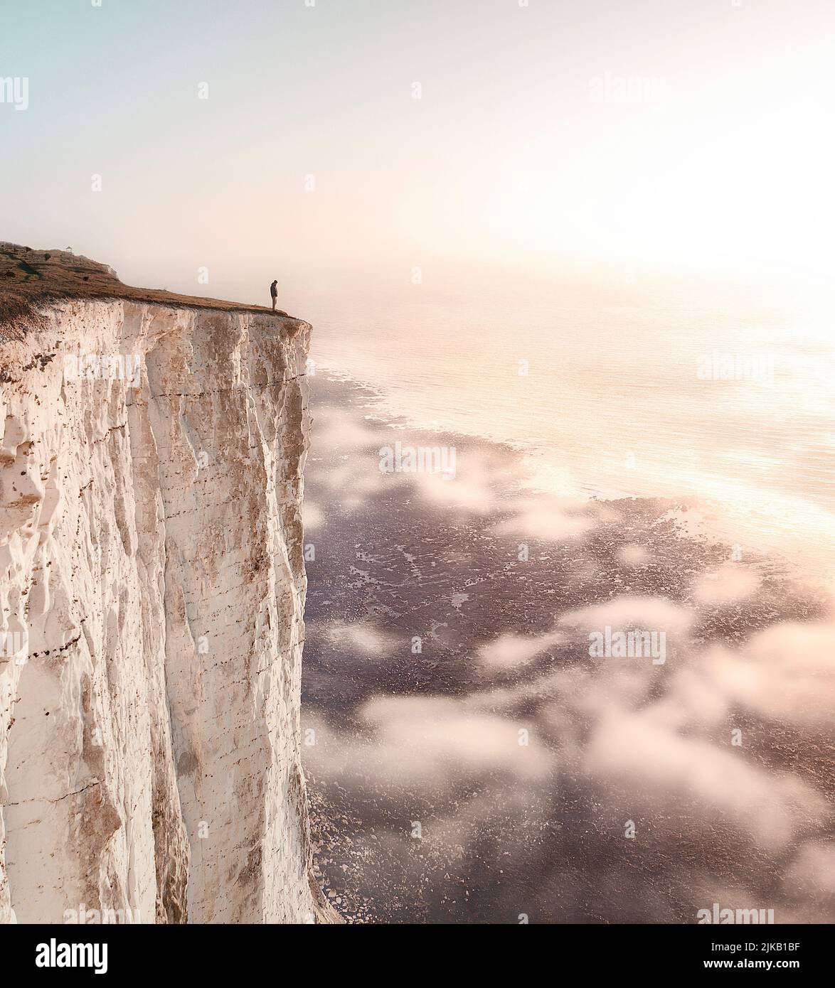 Stood on the edge of the white cliffs of Dover. UK: THESE STUNNING images of a lone traveller crossing incredible landscapes prove how the UK is one o Stock Photo