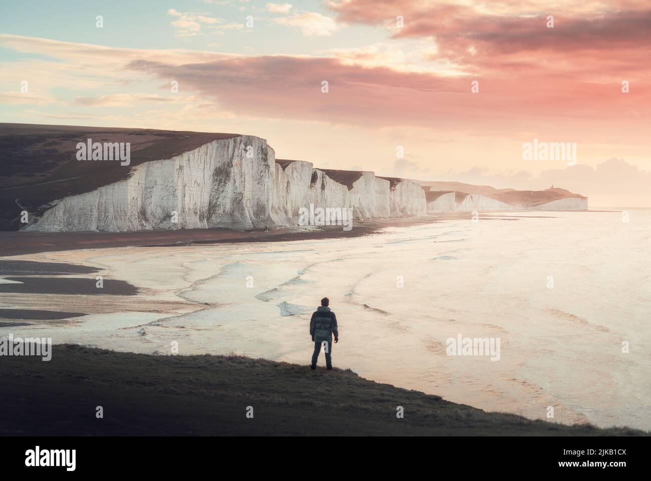A lone traveller looking out on the white cliffs of Dover. UK: THESE STUNNING images of a lone traveller crossing incredible landscapes prove how the Stock Photo