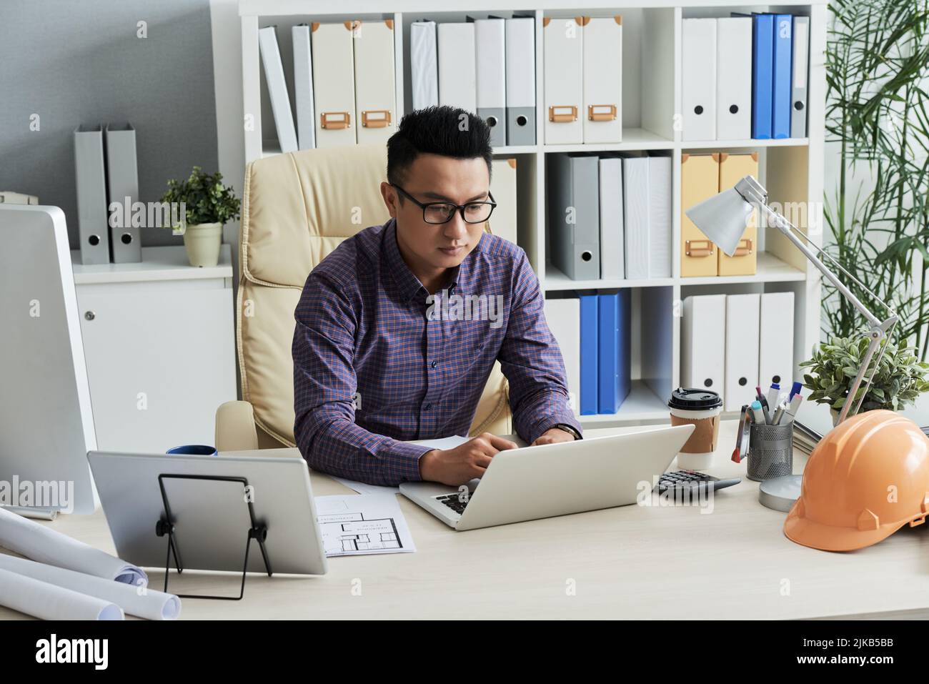 Young Vietnamese engineer working on laptop in his office Stock Photo