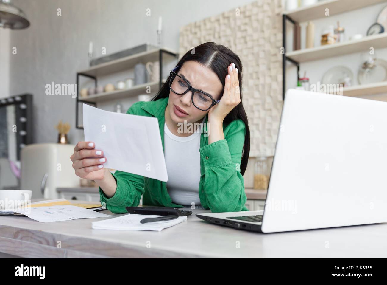 Distressed young woman sit on couch at home read bad negative news in paper correspondence, unhappy biracial female stressed consider unpleasant message in postal letter Stock Photo