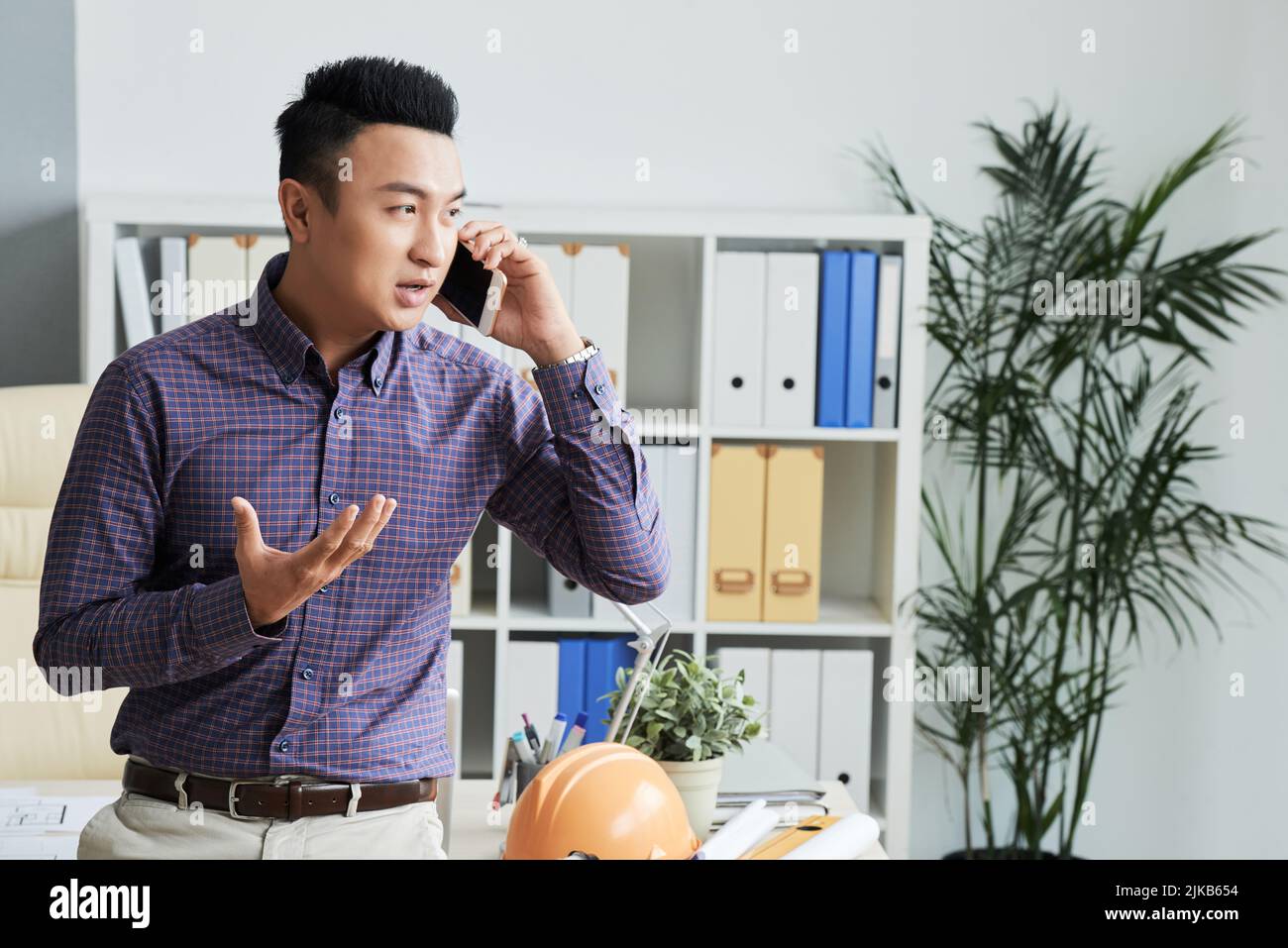 Young Vietnamese engineer talking on the phone with client Stock Photo