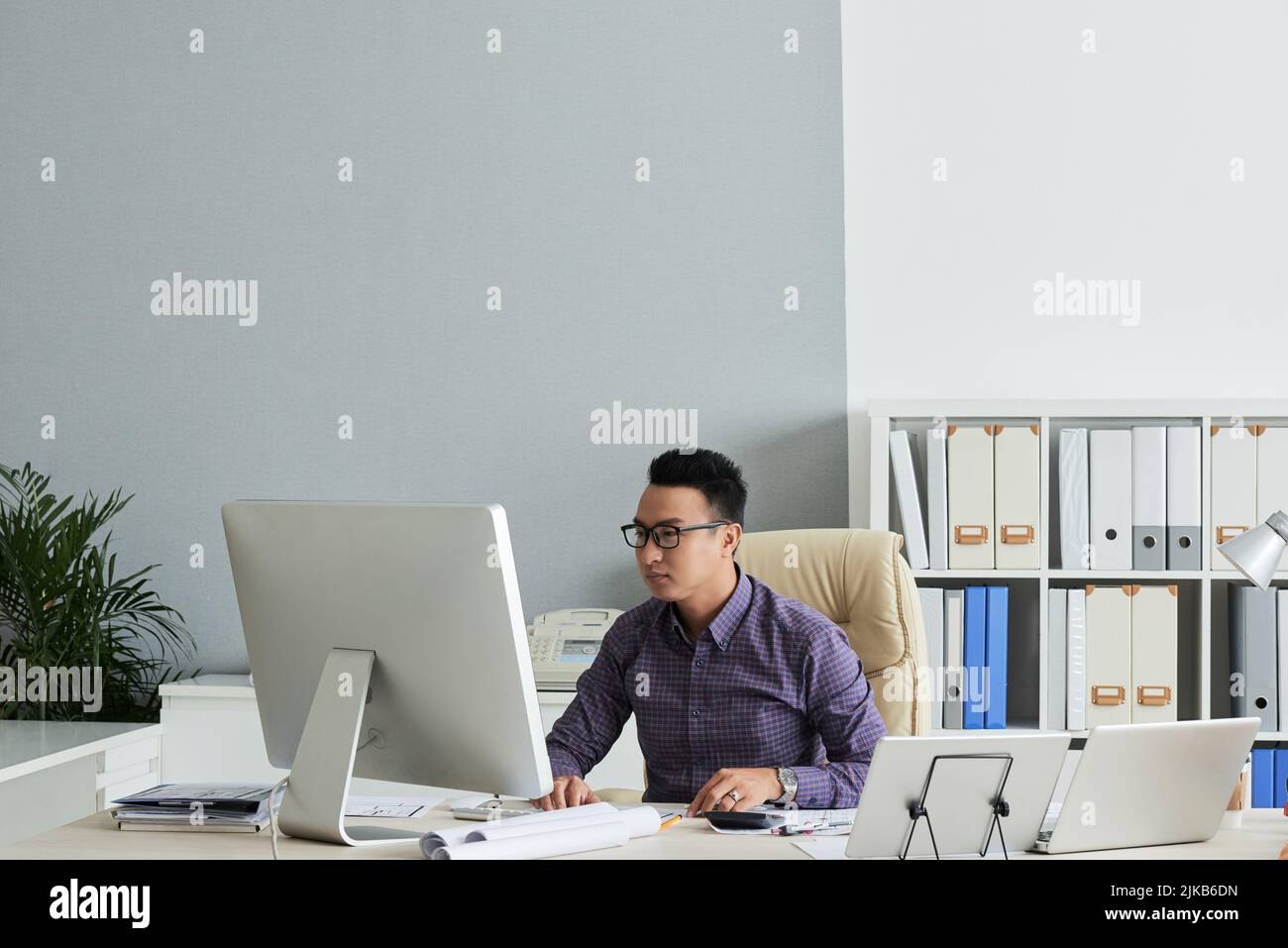 Vietnamese engineer working on computer in his office Stock Photo