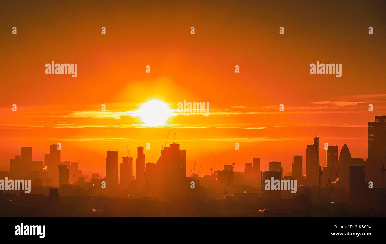 Cityscape of central London skyline with skyscrapers and buildings silhouettes against the rising sun. View from Parliament Hill, Hampstead Heath. UK. Stock Photo