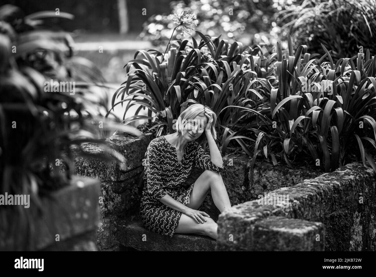 A woman sits on a stone bench in old parkl. Black and white photo. Stock Photo