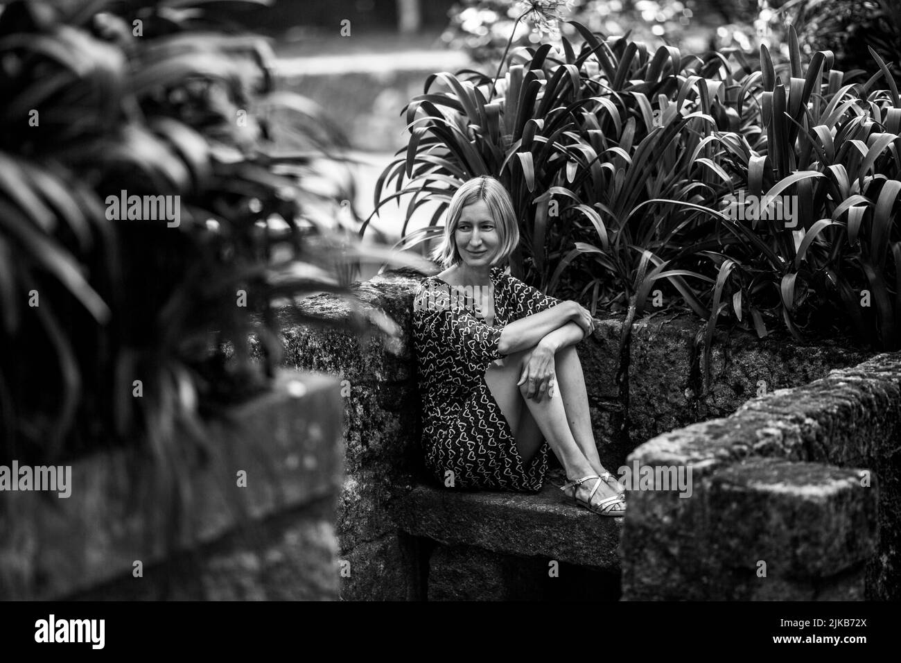 A woman on a stone bench in old parkl. Black and white photo. Stock Photo