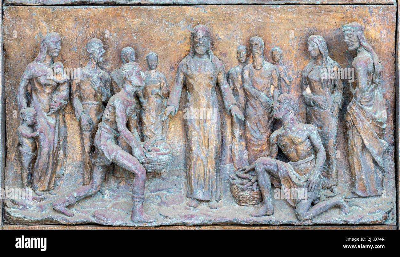 MONOPOLI, ITALY - MARCH 6, 2022: The bronze relief Miralce The Feeding the multitude on the gate of church Chiesa di Sacro Cuore by Wolfgang Stempfele Stock Photo