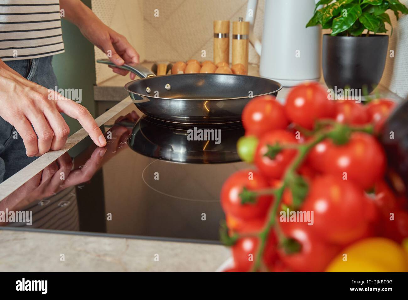 Modern kitchen appliance, Woman hand turn on induction stove with steel frying pan, Finger