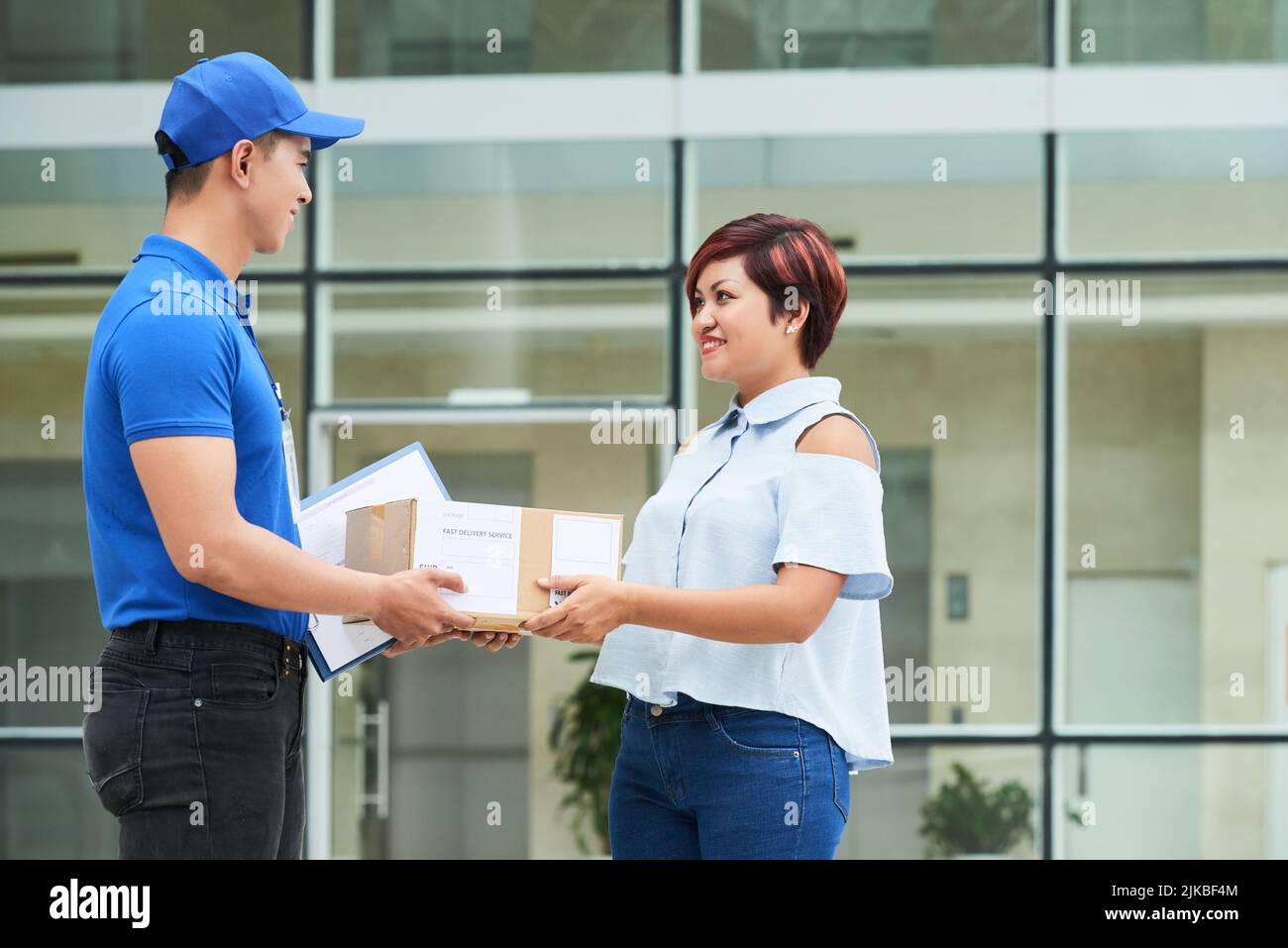 Vietnamese delivery man giving packages to smiling woman Stock Photo