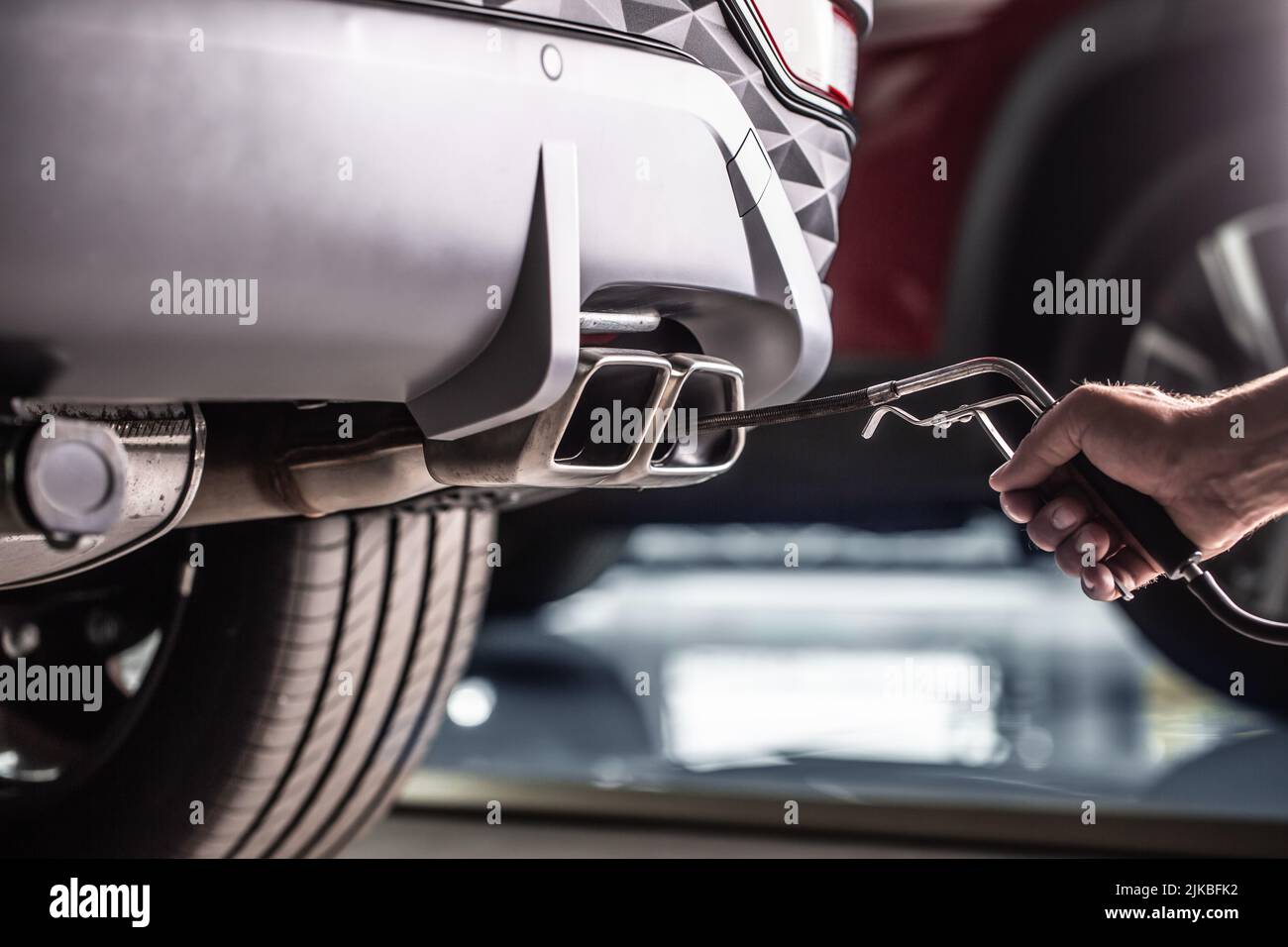 Measurement of exhaust emissions at the technical inspection station. A car repairman applies a probe to the exhaust. Stock Photo