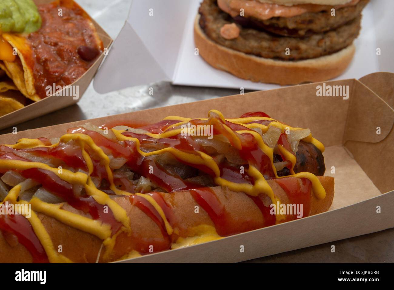 Selection of street food hot dog, chilli nachos and burger serving suggestion. Stock Photo
