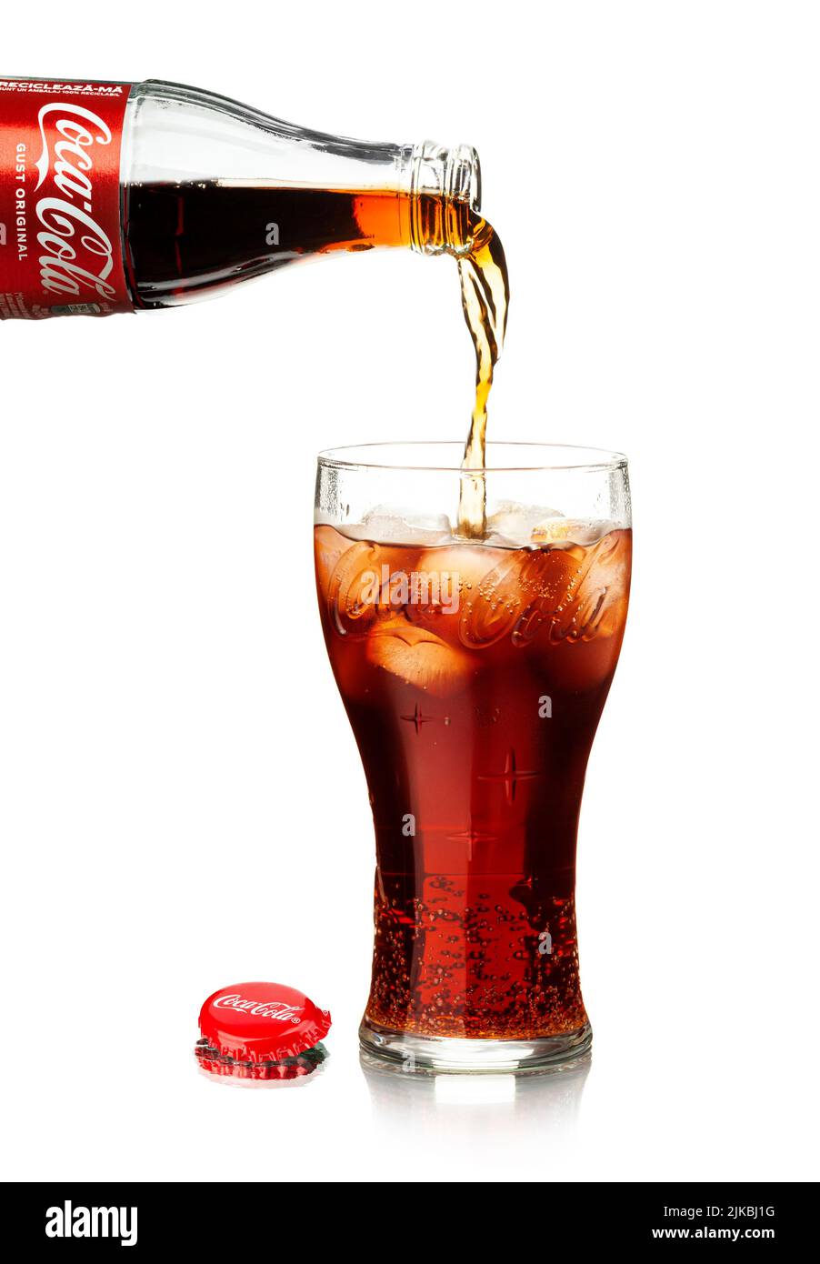 Chisinau, Moldova - July 31, 2022: Pouring cola from bottle into glass with splashing. Classic bottle Of Coca-Cola isolated on white background Stock Photo