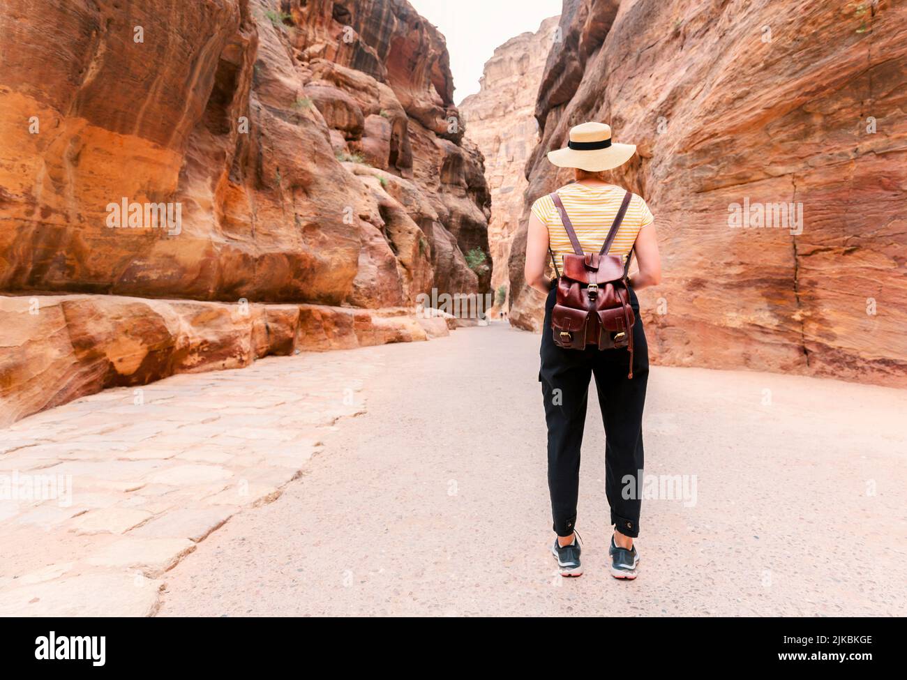 Petra, Jordan - Tourist with hat in Siq gorge in Petra historic and archaeological city in southern Jordan Stock Photo