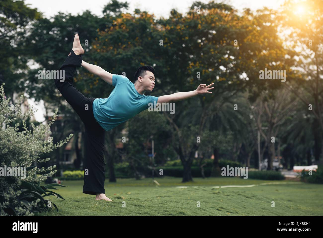 Handsome young Vietnamese man practicing yoga outdoors Stock Photo