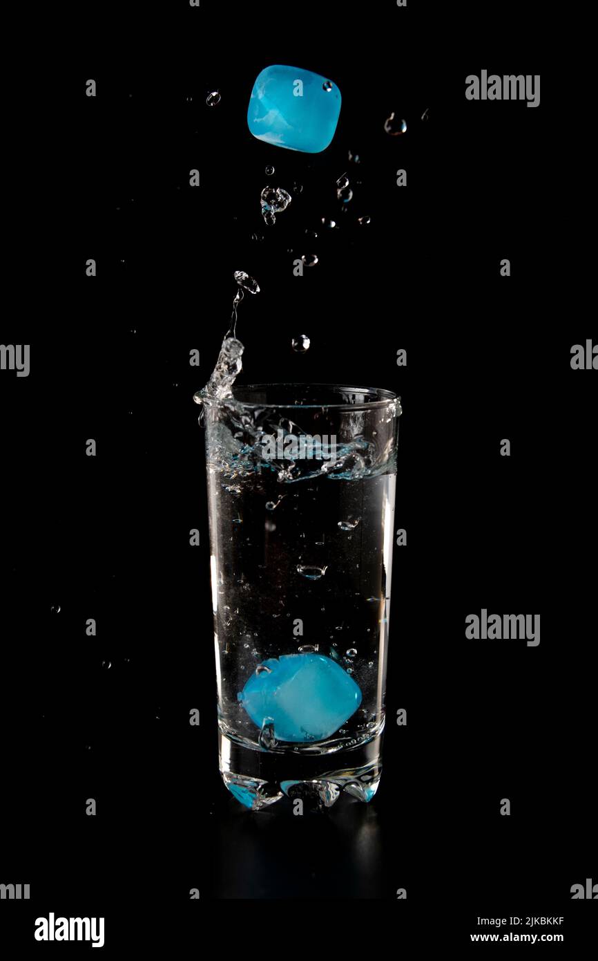 Colour Ice cubes thrown to a glass of water from above with splash on a ...
