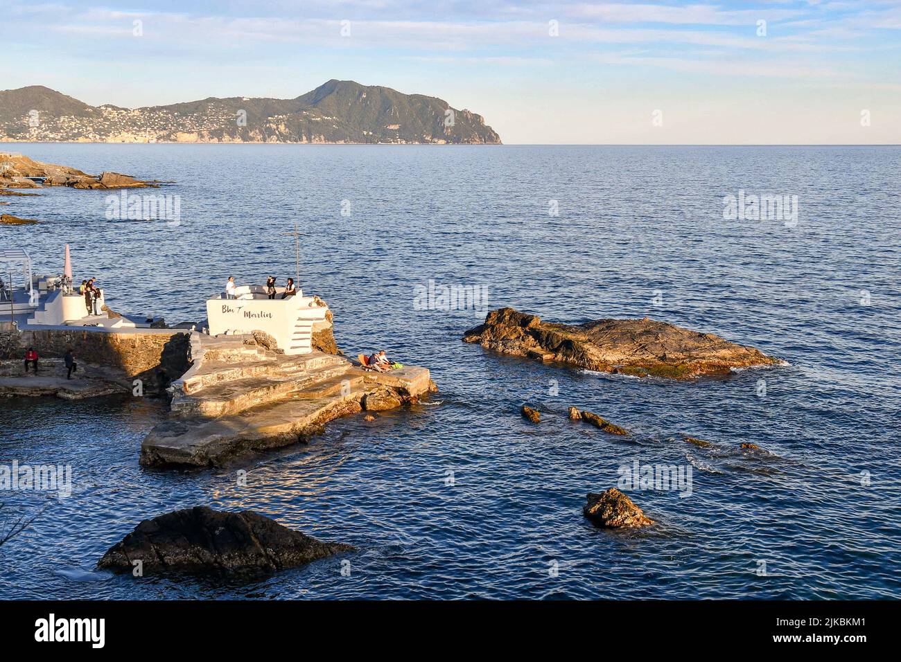 View of the Paradise Gulf with people in an outdoor cafè on a cliff of the Anita Garibaldi Promenade and the Promontory of Portofino, Nervi, Genoa Stock Photo