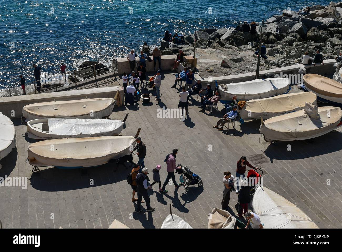 High-angle view of the quay with tourists, fishermen and dry boats in a sunny Easter Monday, Boccadasse, Genoa, Liguria, Italy Stock Photo