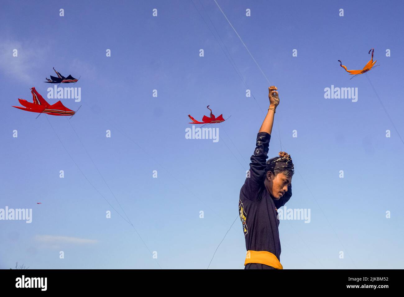 Denpasar, Indonesia. 31st July, 2022. A man seen drawing a kite string.  Thousands of people flock to Mertasari Beach in Sanur for a kite festival  during Bali's kite season, which runs from