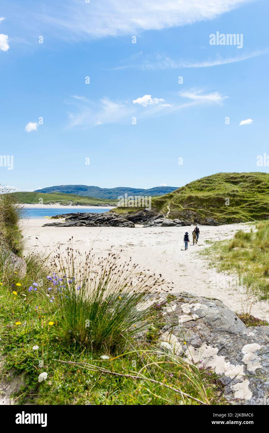 Walkers on Ballinreavy Strand beside Sheskinmore Nature Reserve. Sheskinmore refers to a large area of sand dunes, lake and marsh that lies between Ki Stock Photo