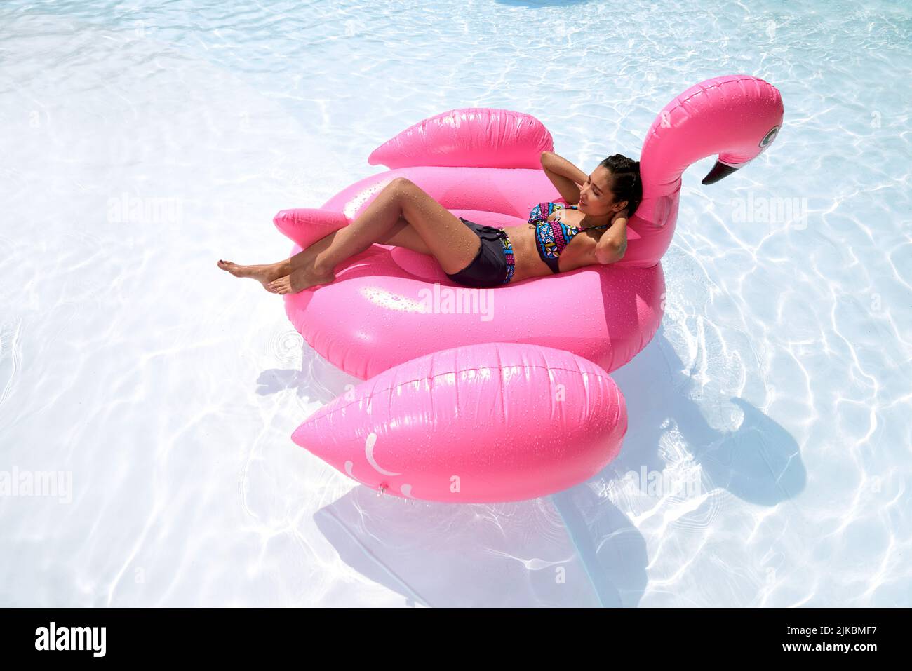 Beautiful young Vietnamese woman floating on inflatable flamingo Stock Photo