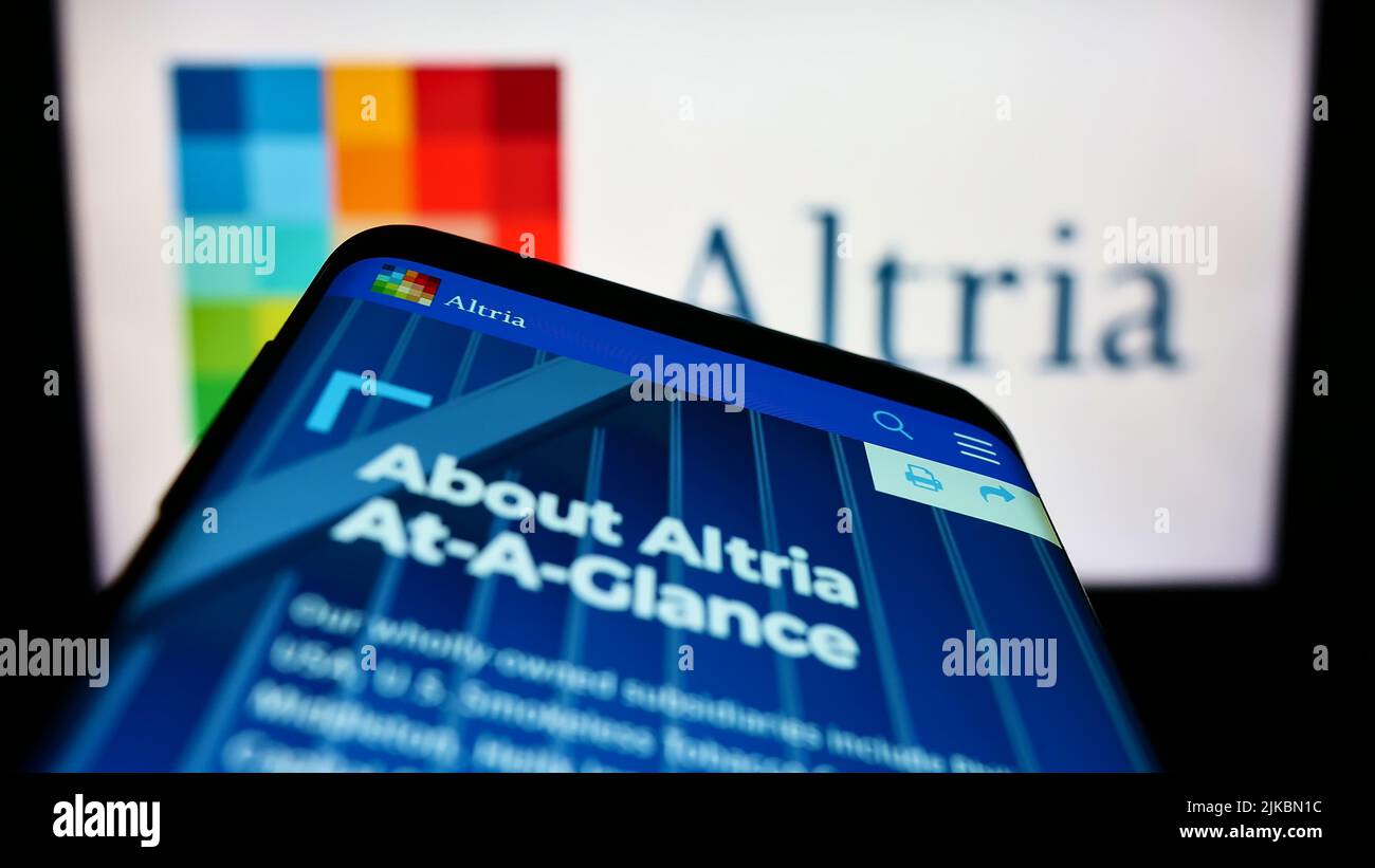 Smartphone with website of US tobacco company Altria Group Inc. on screen in front of business logo. Focus on top-left of phone display. Stock Photo
