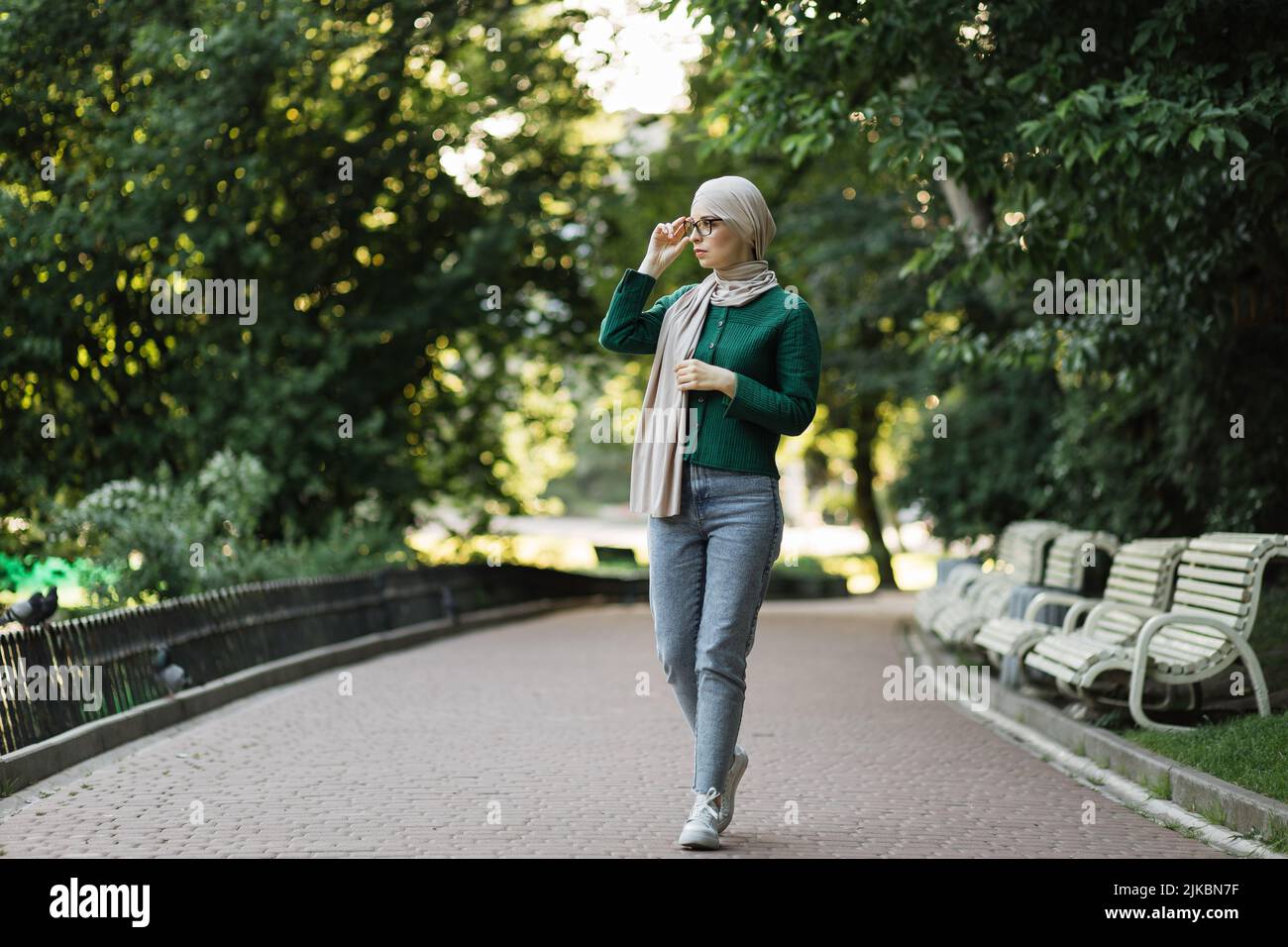 Portrait of smiling young muslim woman touching her eyeglass during