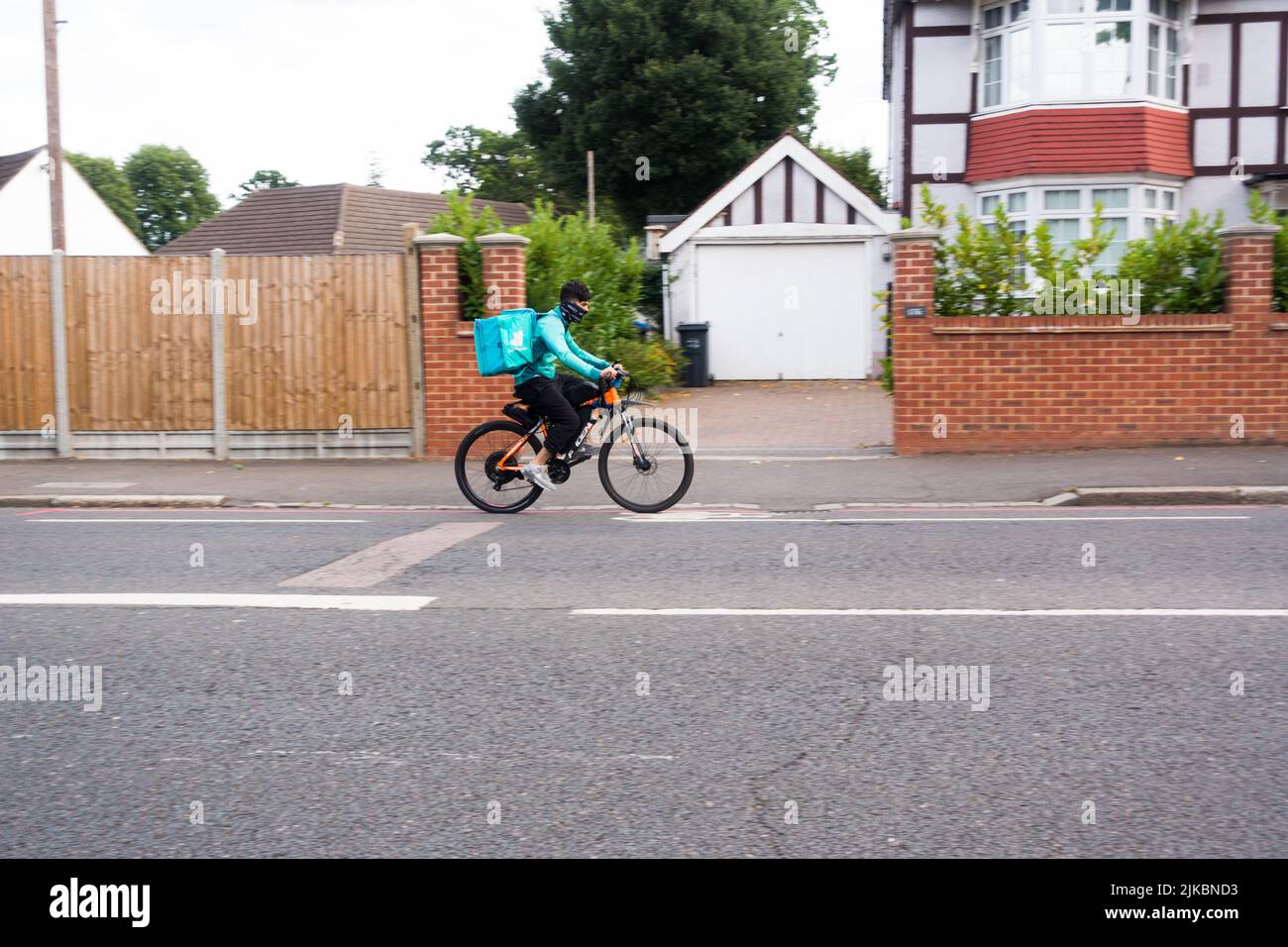 Deliveroo rider with backpack container riding on electric bike Stock Photo