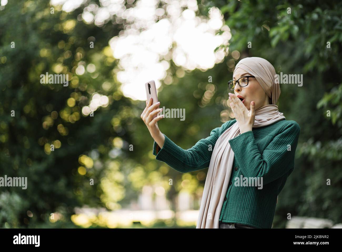 Pretty smiling muslim business woman in hijab walks around the park and ...