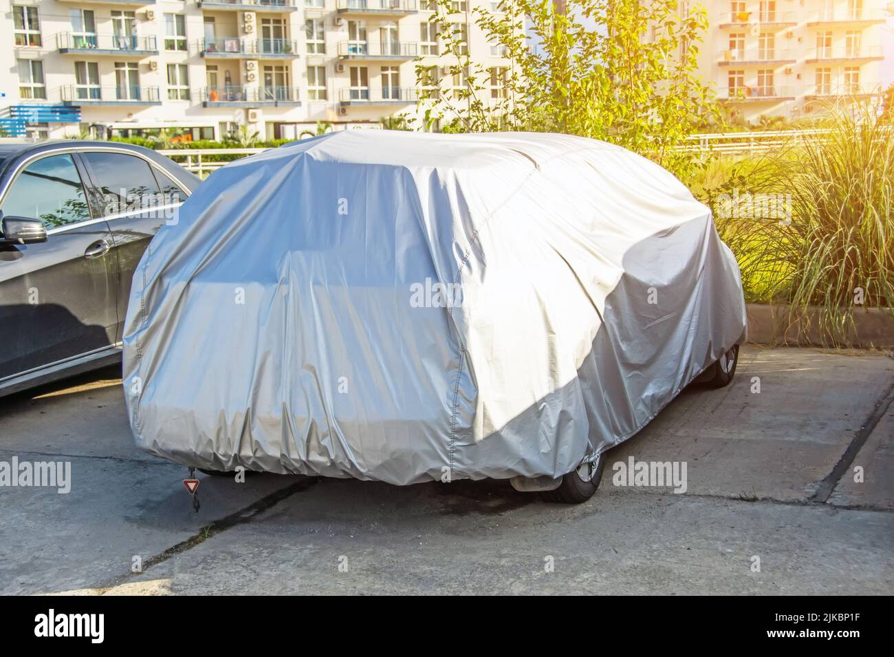 The car is covered with a protective cover from the effects of rain and