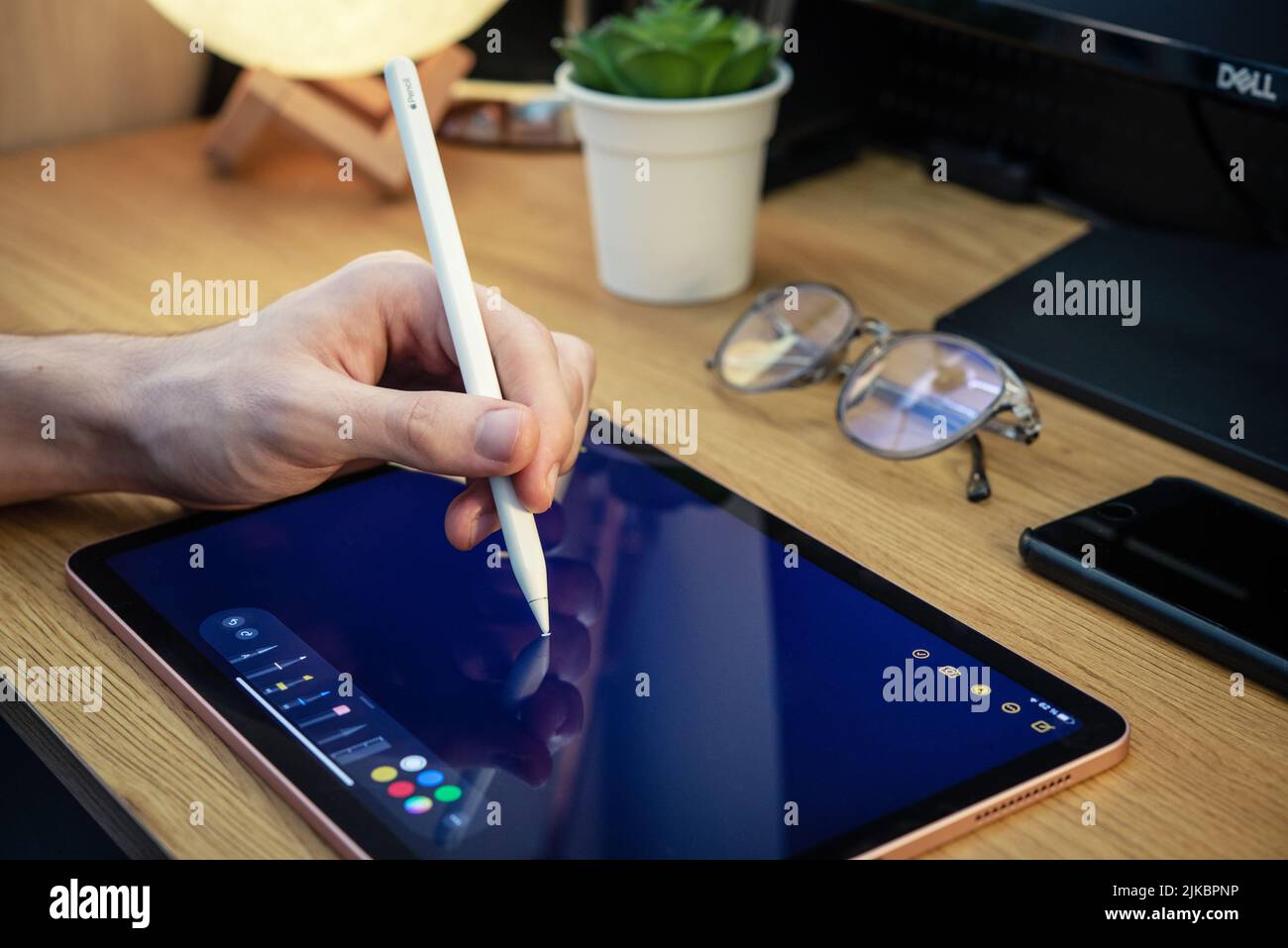 KIEV, UKRAINE - DECEMBER 21, 2021:Man with Apple Pencil using iPad Pro for drawing. iPad Pro was created and developed by the Apple inc. Stock Photo