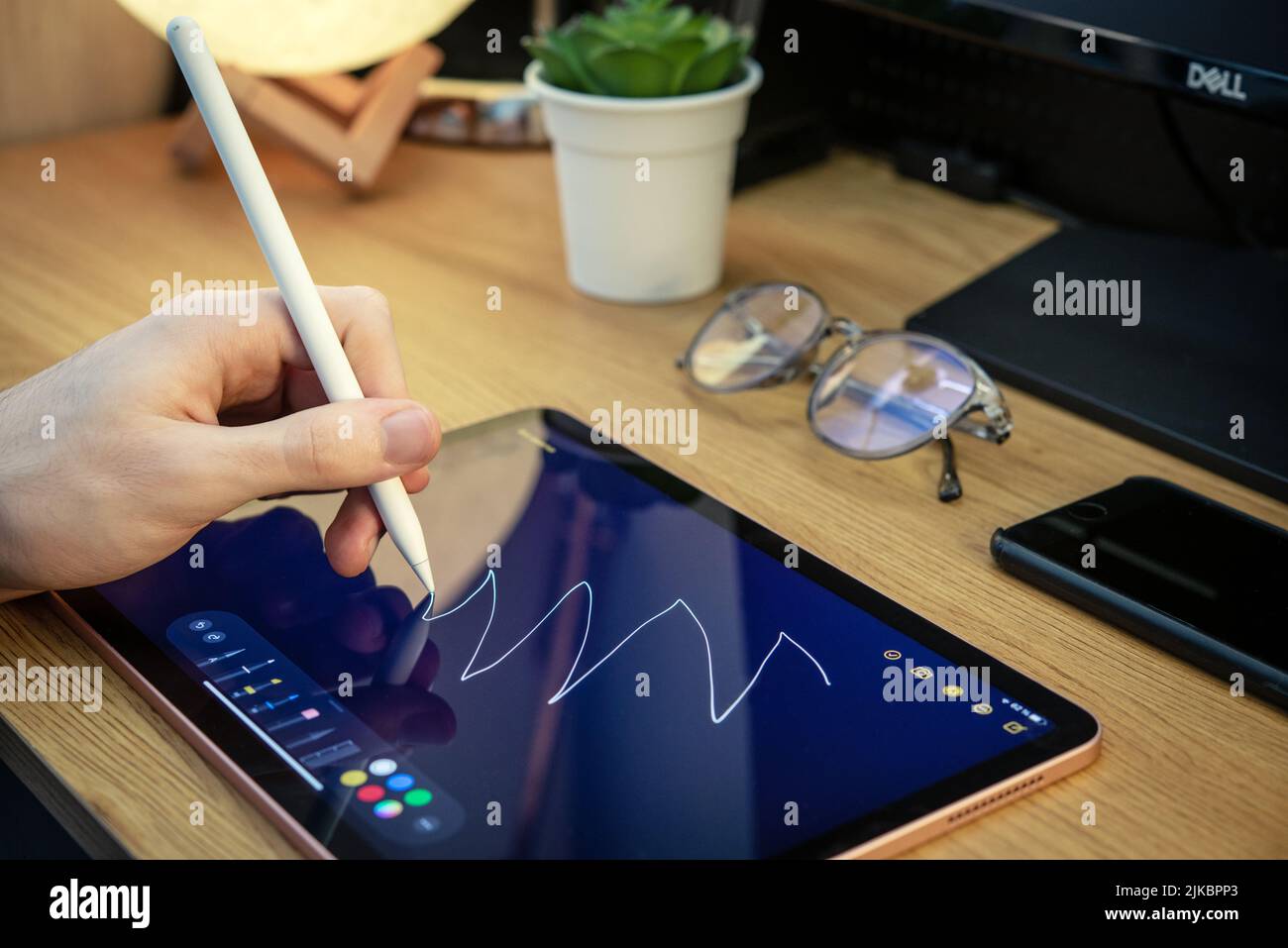 KIEV, UKRAINE - DECEMBER 21, 2021:Man with Apple Pencil using iPad Pro for drawing. iPad Pro was created and developed by the Apple inc. Stock Photo