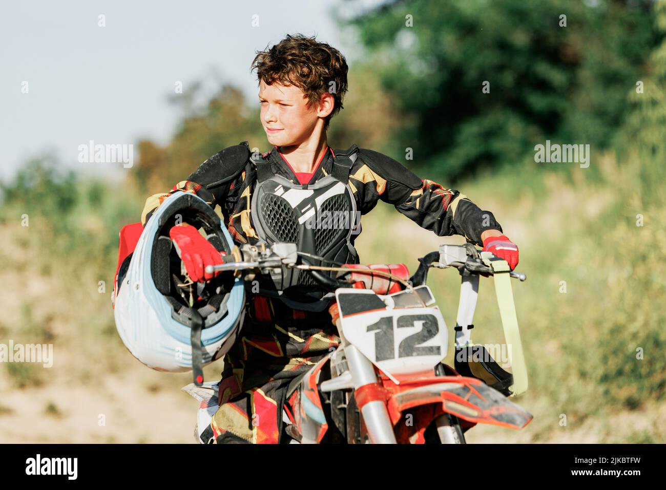 Live shot of junior sportsman, motorcyclist training on motorbike at hot summer day, outdoors