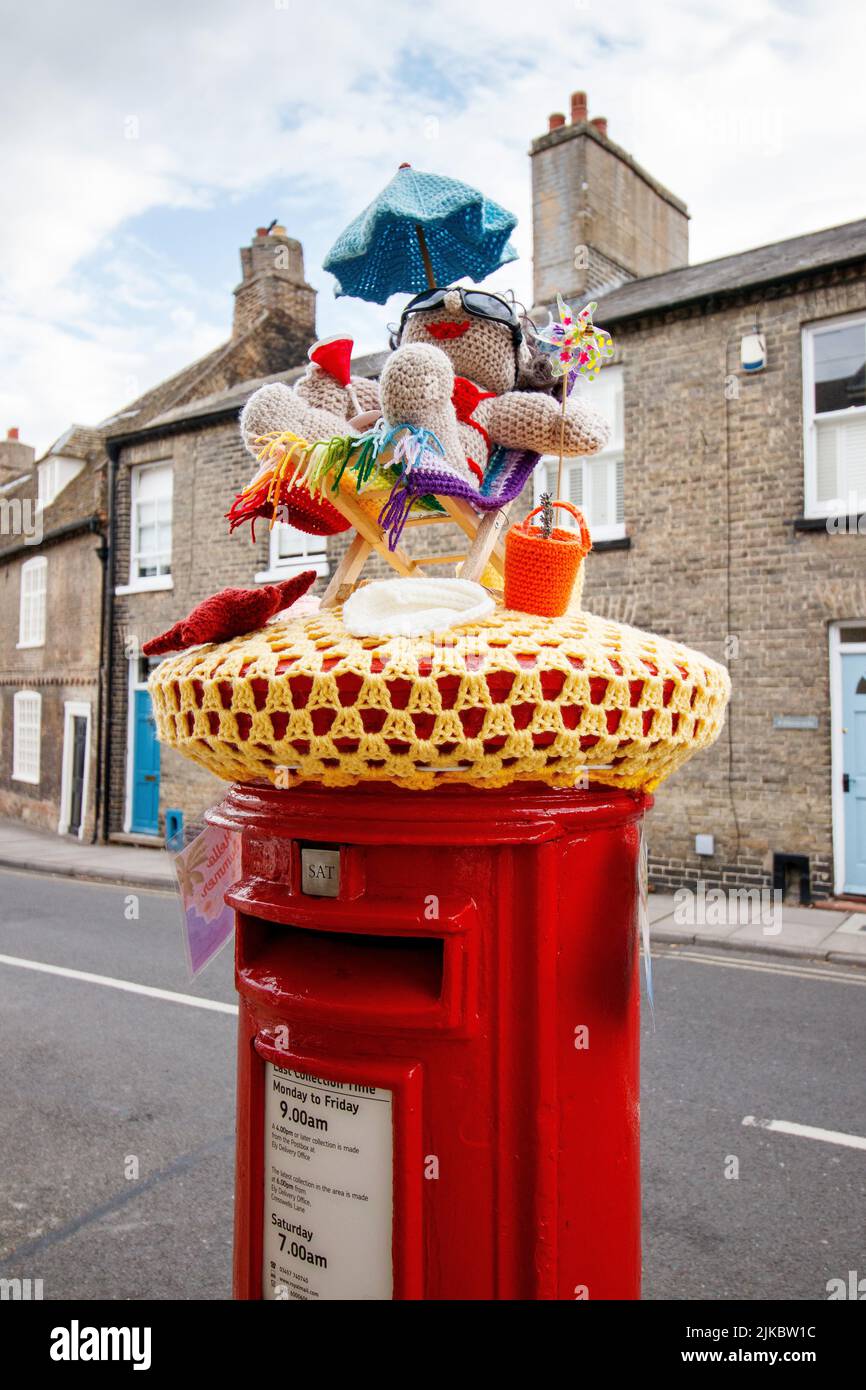 A knitted decoration on top of a post box in Ely, Cambridgeshire welcoming in summer. Stock Photo