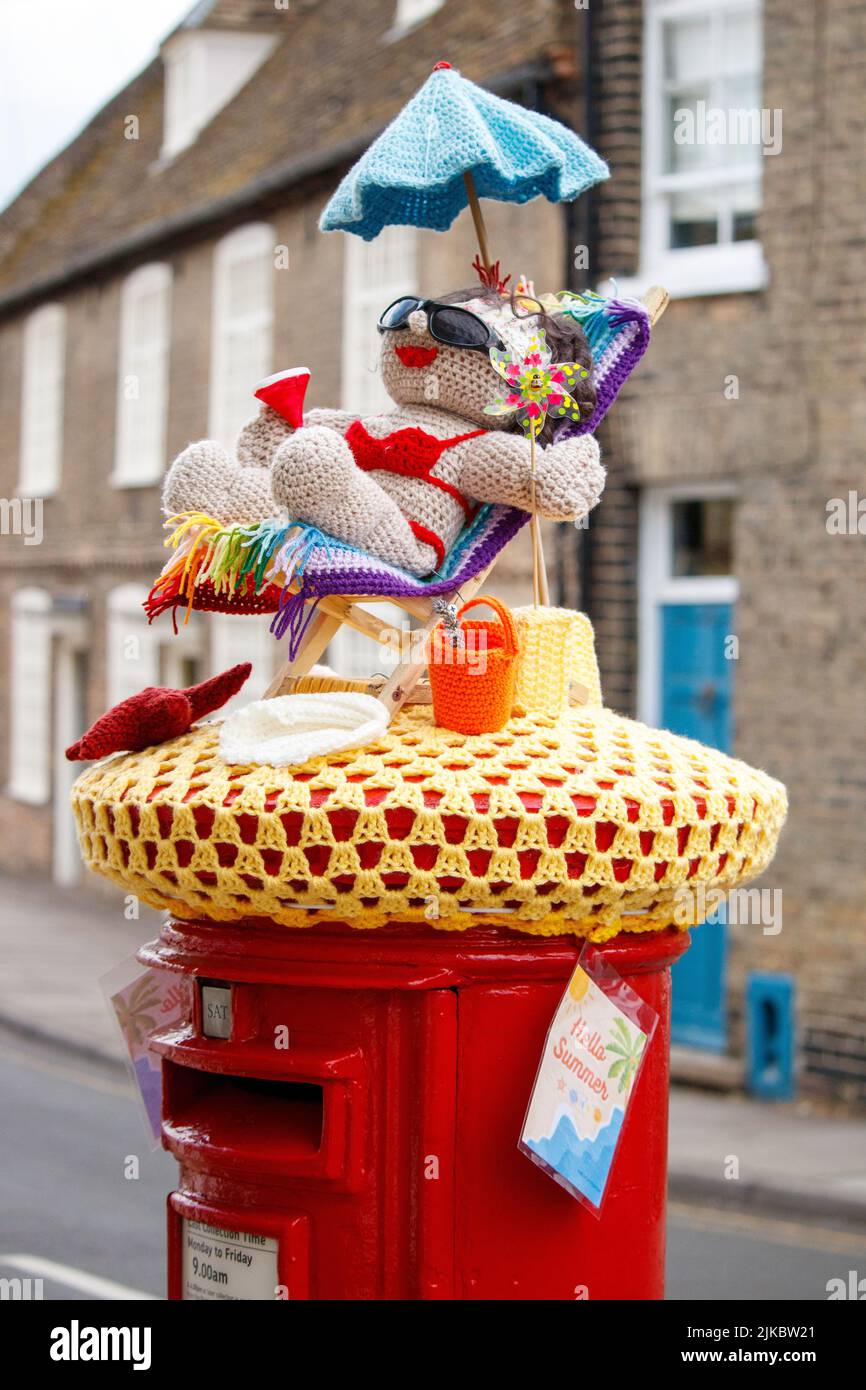 A knitted decoration on top of a post box in Ely, Cambridgeshire welcoming in summer. Stock Photo