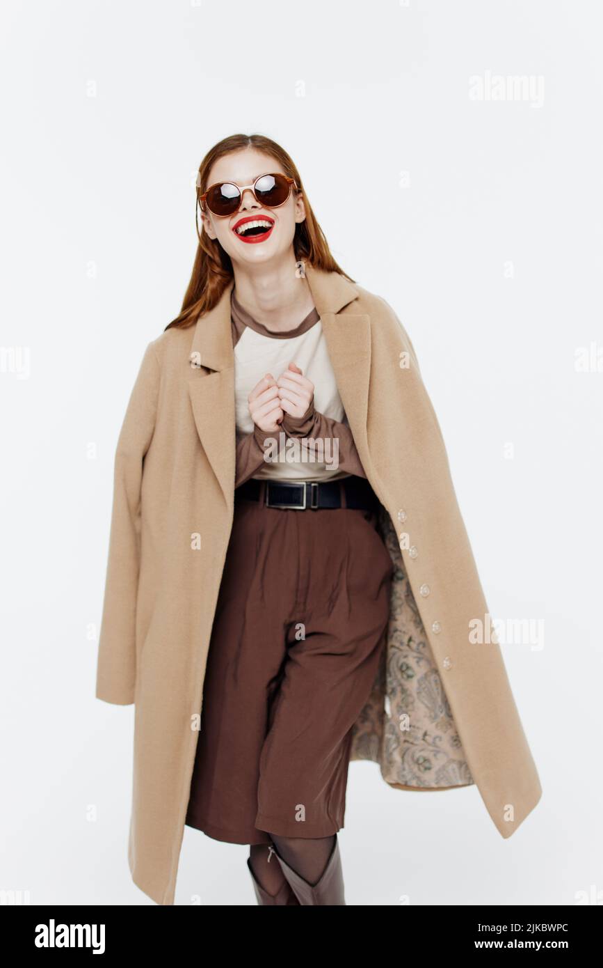 Cheerful laughing cute redhead young woman posing in glasses coat on a