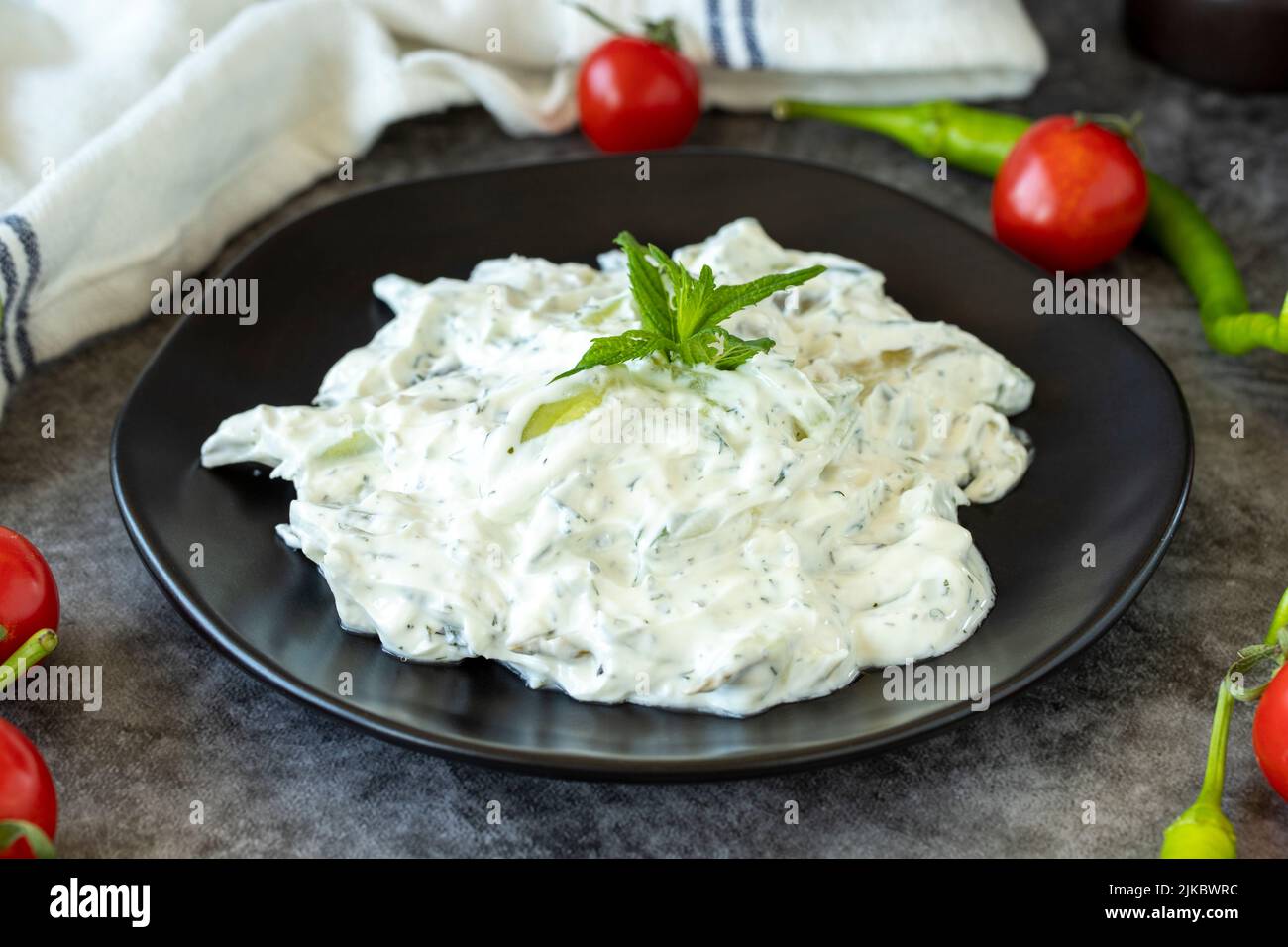 Fresh yoghurt appetizer. Dry tzatziki on a dark background. Cacik made with mint, salad and yogurt. Healthy meals. Local name kuru cacik .Close up Stock Photo