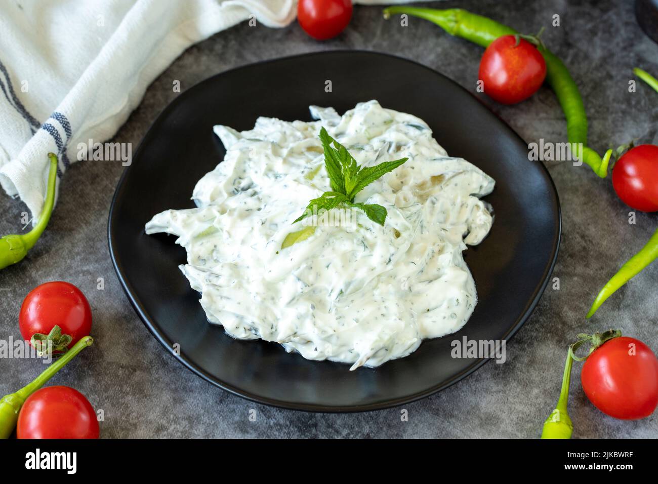 Fresh yoghurt appetizer. Dry tzatziki on a dark background. Cacik made with mint, salad and yogurt. Healthy meals. Local name kuru cacik .Close up Stock Photo
