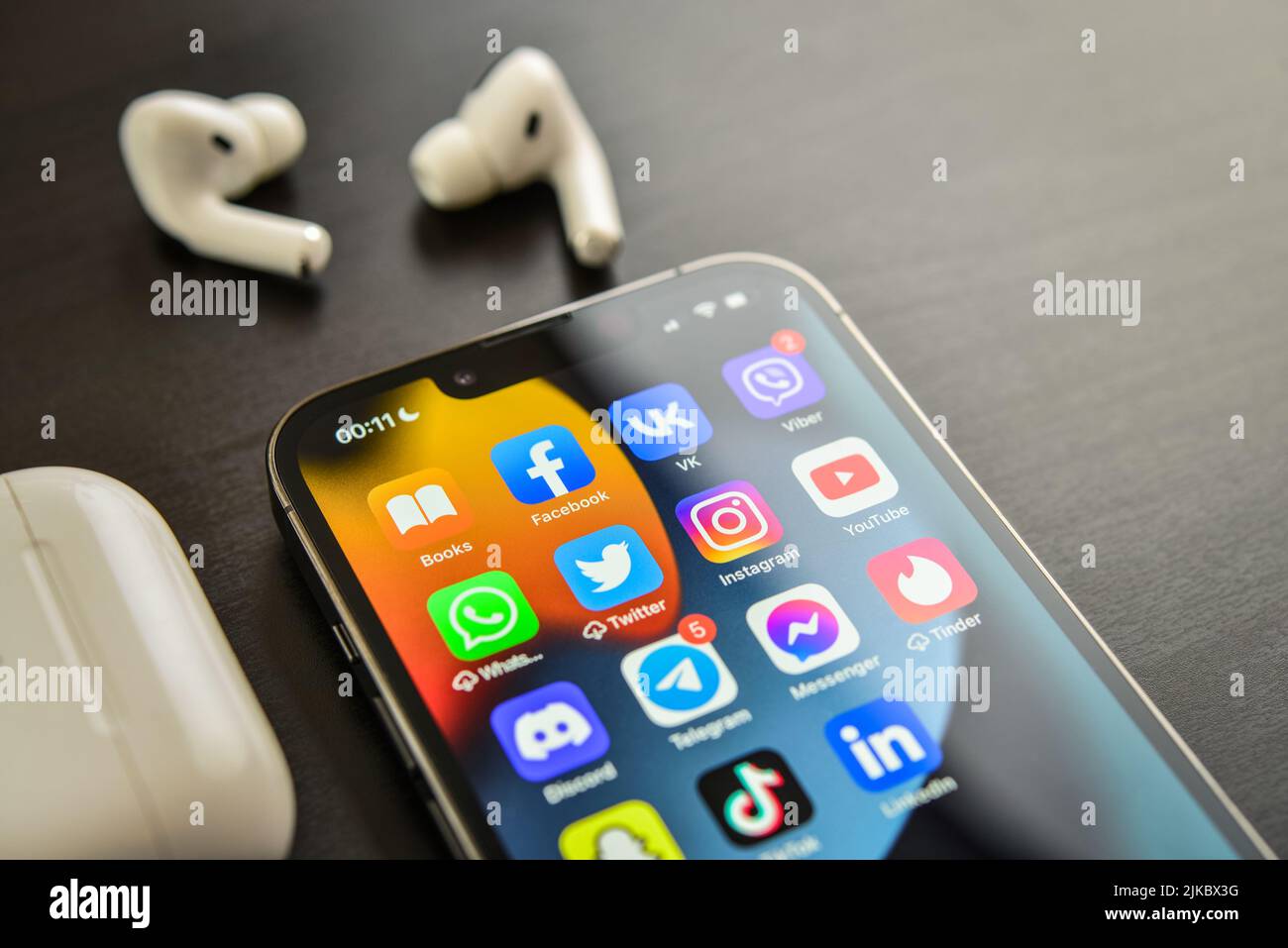 KIEV, UKRAINE - FEBRUARY 10, 2022:  Social media icons on screen of  iPhone 13 Pro with AirPods Pro headphones. Social media are most popular tool for Stock Photo