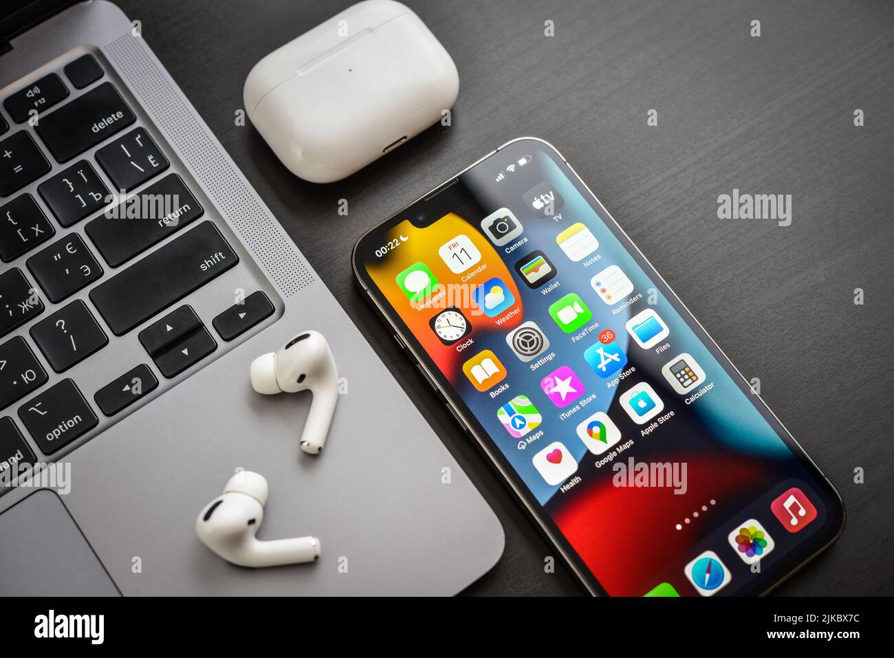 KIEV, UKRAINE - FEBRUARY 10, 2022: Apple product. MacBook Pro, iPhone 13 Pro with AirPods Pro headphones on a black background top view. Technology ga Stock Photo