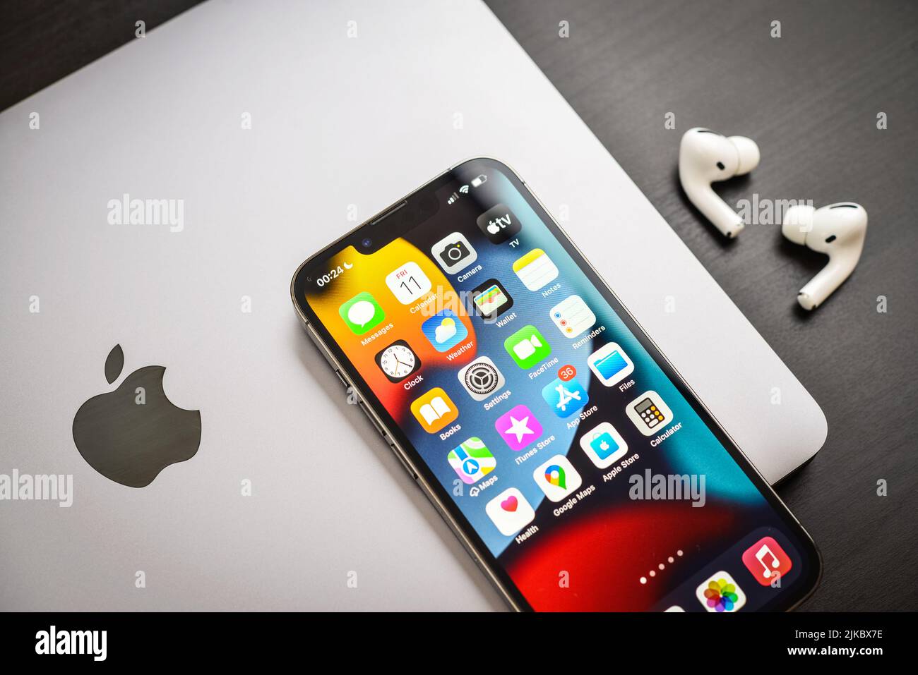 KIEV, UKRAINE - FEBRUARY 10, 2022: Apple product. MacBook Pro, iPhone 13 Pro with AirPods Pro headphones on a black background top view. Technology ga Stock Photo
