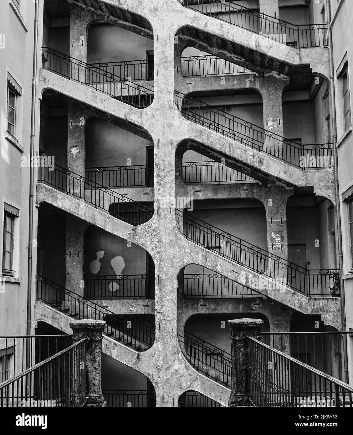 A grayscale of an old apartment building with an outdoor staircase Stock Photo