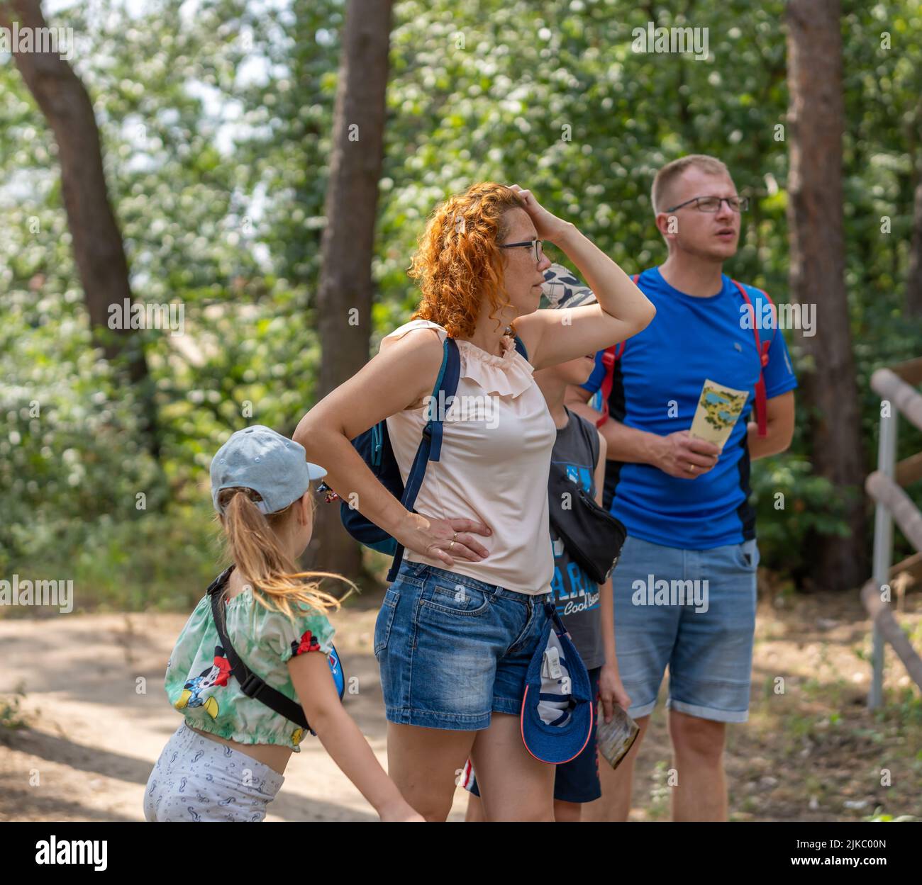 A Woman, man and kid girl holding a map and looking at something in the zoo Stock Photo