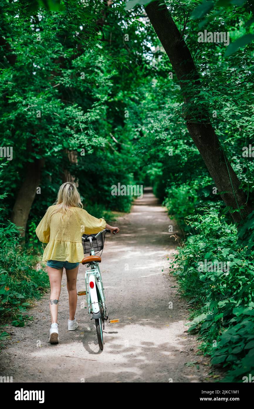 young blonde girl about to ride a bike on a trail summer outside Stock Photo