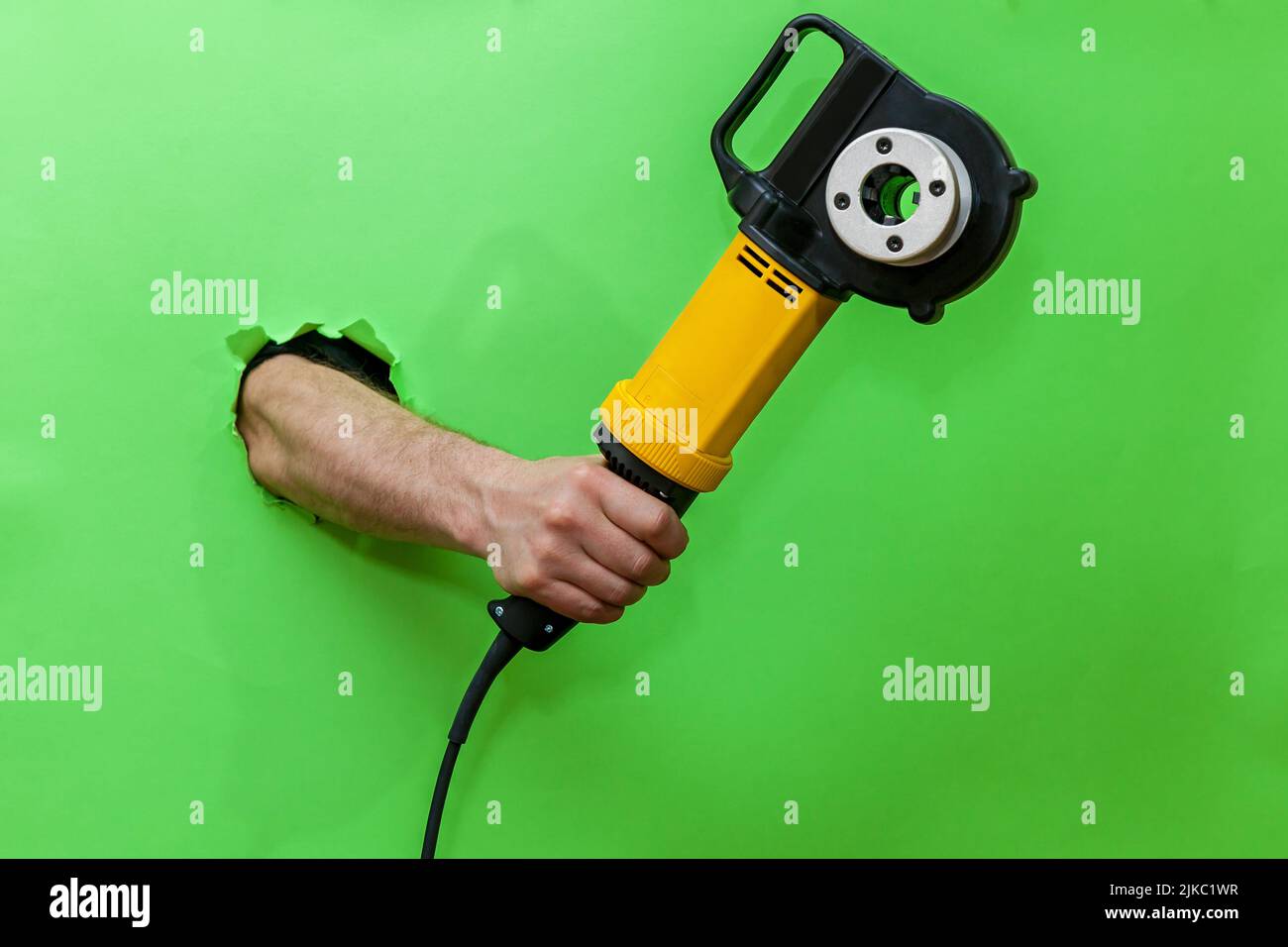 Thread cutting tool. A hand on a green background holds a power tool