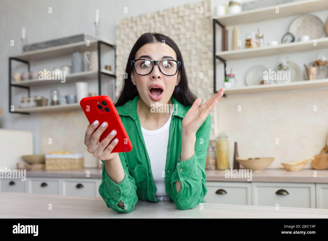 Shocked young woman looking at smartphone screen, feeling confused getting message with unbelievable news. Surprised millennial lady getting unexpected online lottery win notification at home. Stock Photo