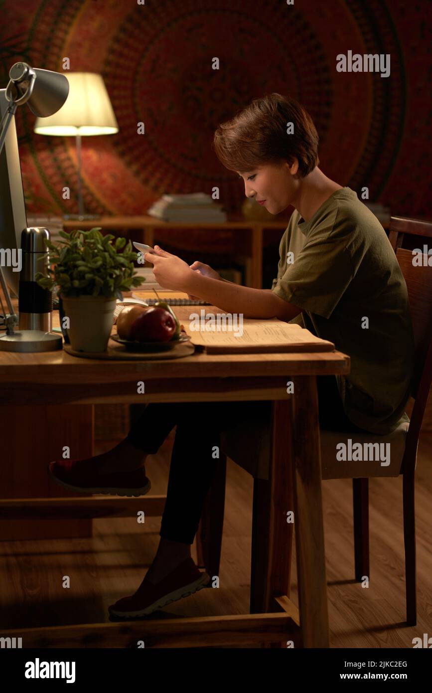 Side view of college student using digital tablet while doing homework in the light of lamp Stock Photo