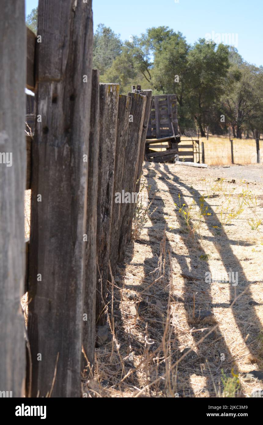 A vertical shot of a wooden fence on a farm in a rural area on a sunny ...