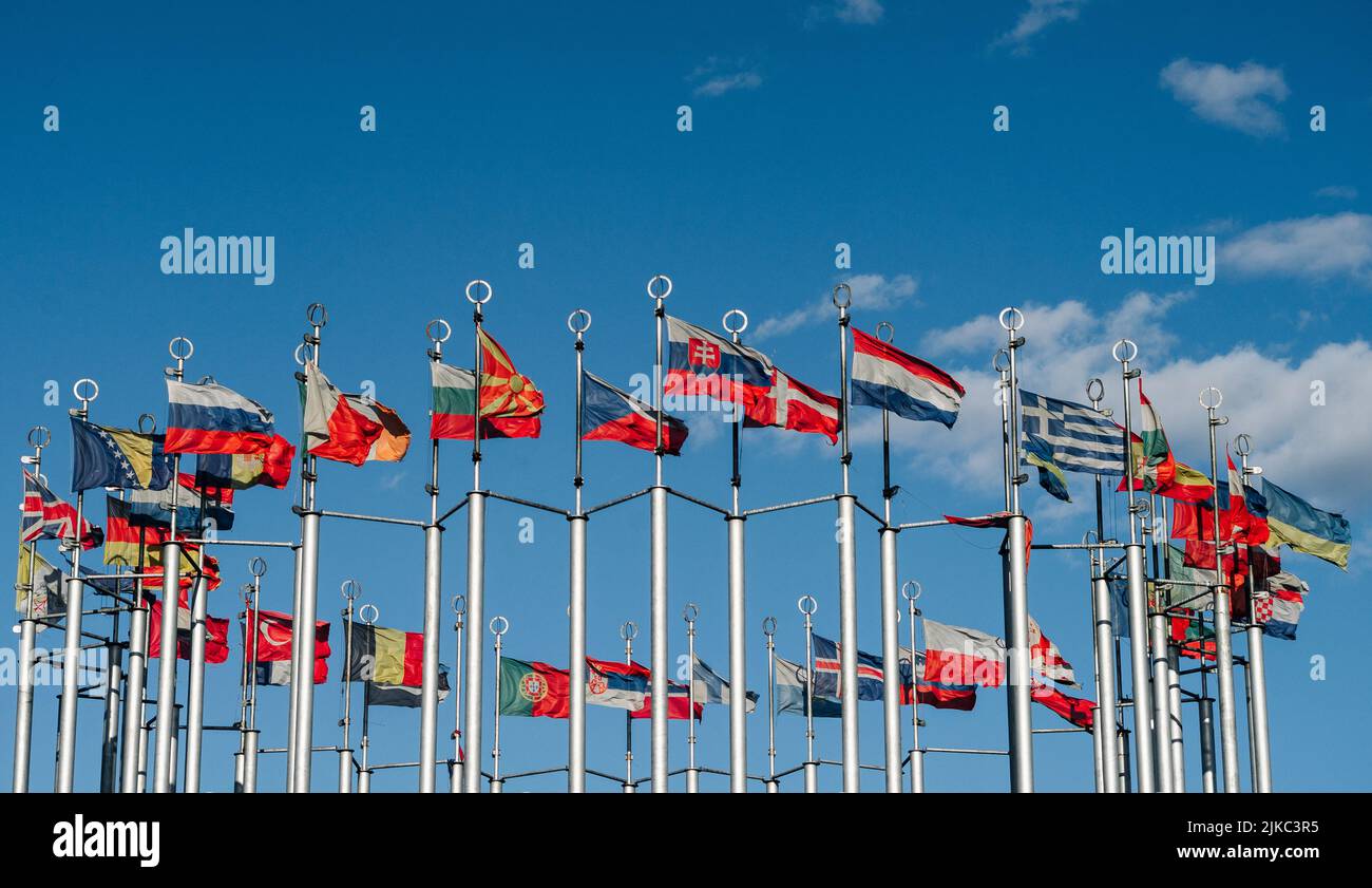 flags of the countries of the world on flagpoles against the blue sky ...