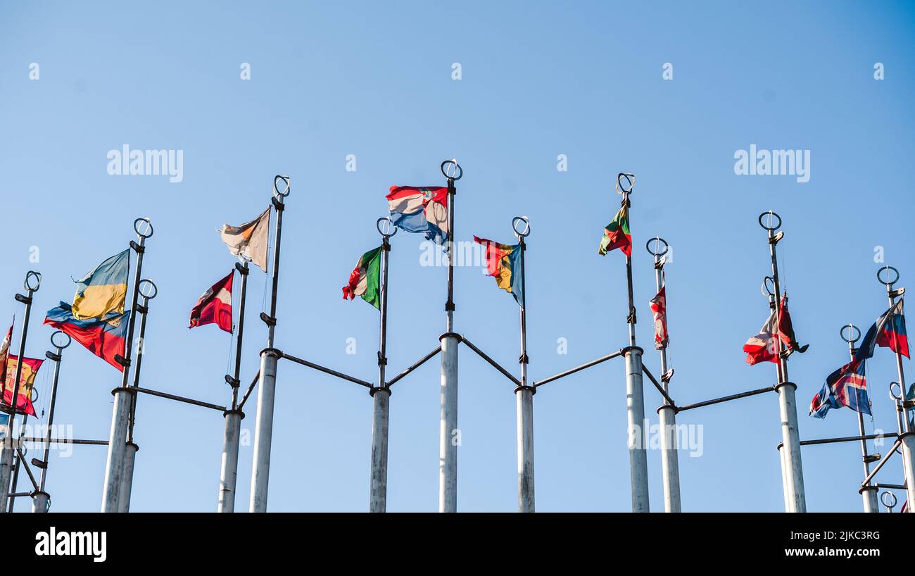 flags of the countries of the world on flagpoles against the blue sky ...