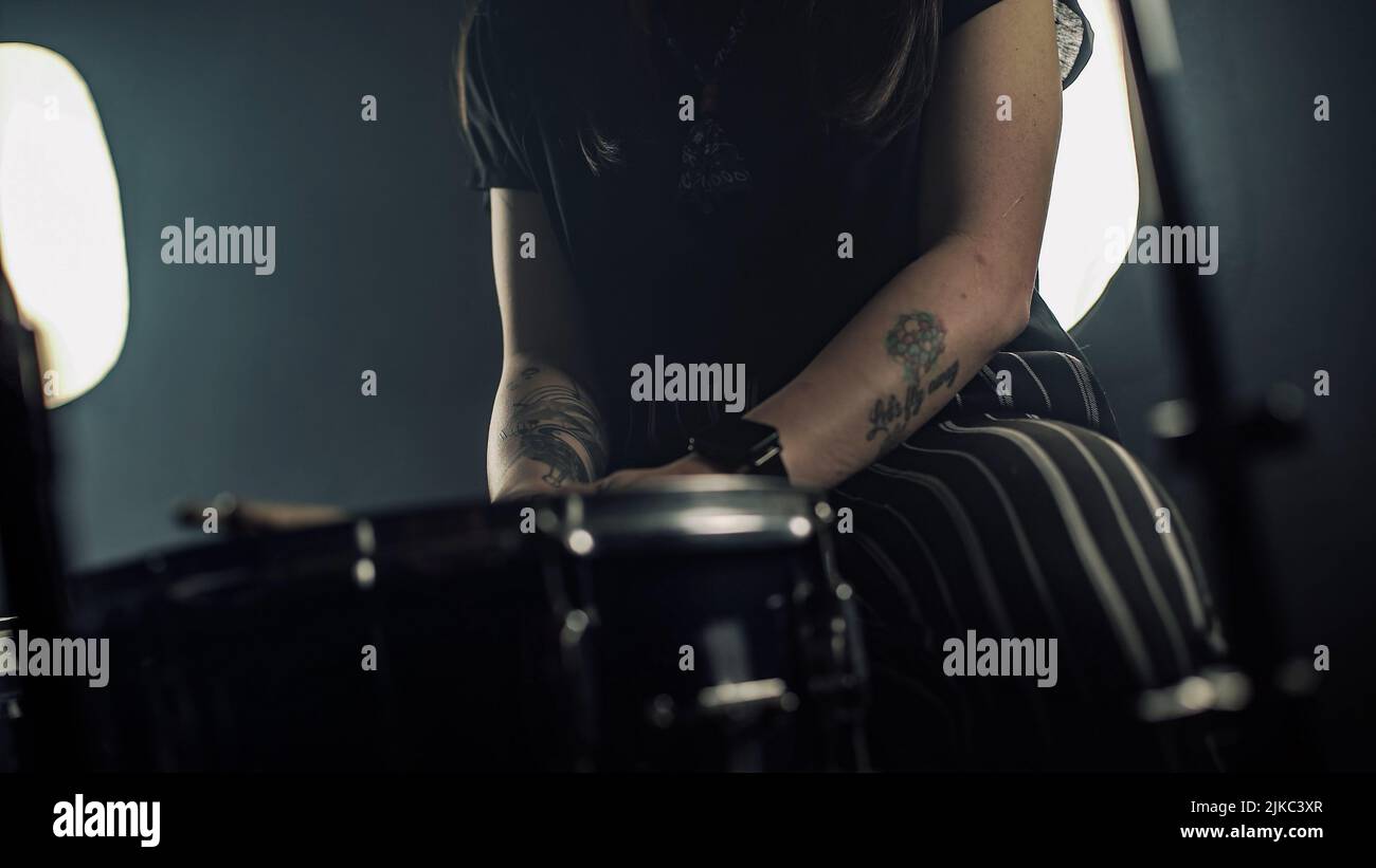 Exhausted female drummer with glasses sits near a drum set after the performance Stock Photo